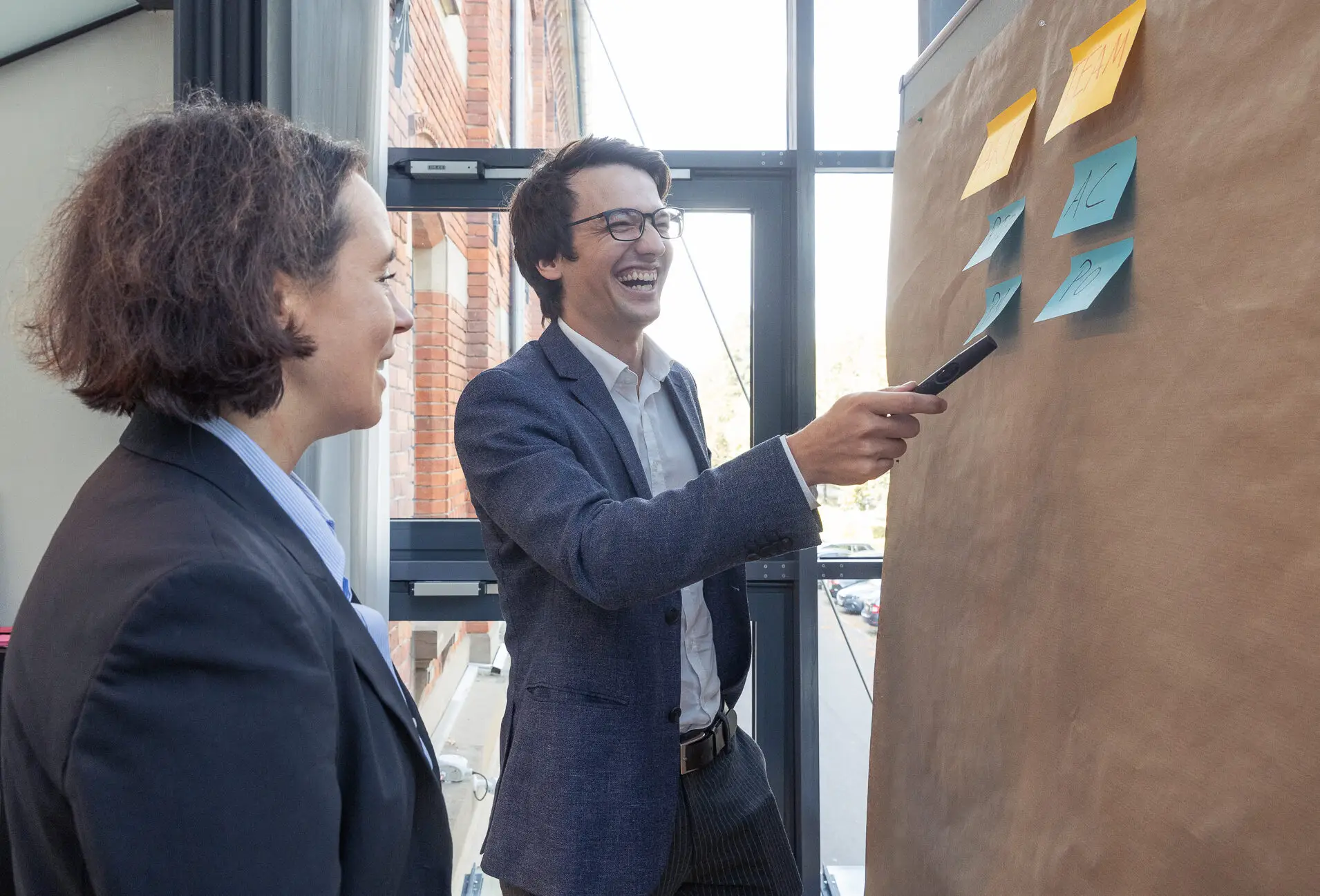 Julia und Yannick brainstormen gut gelaunt an der Pinwand